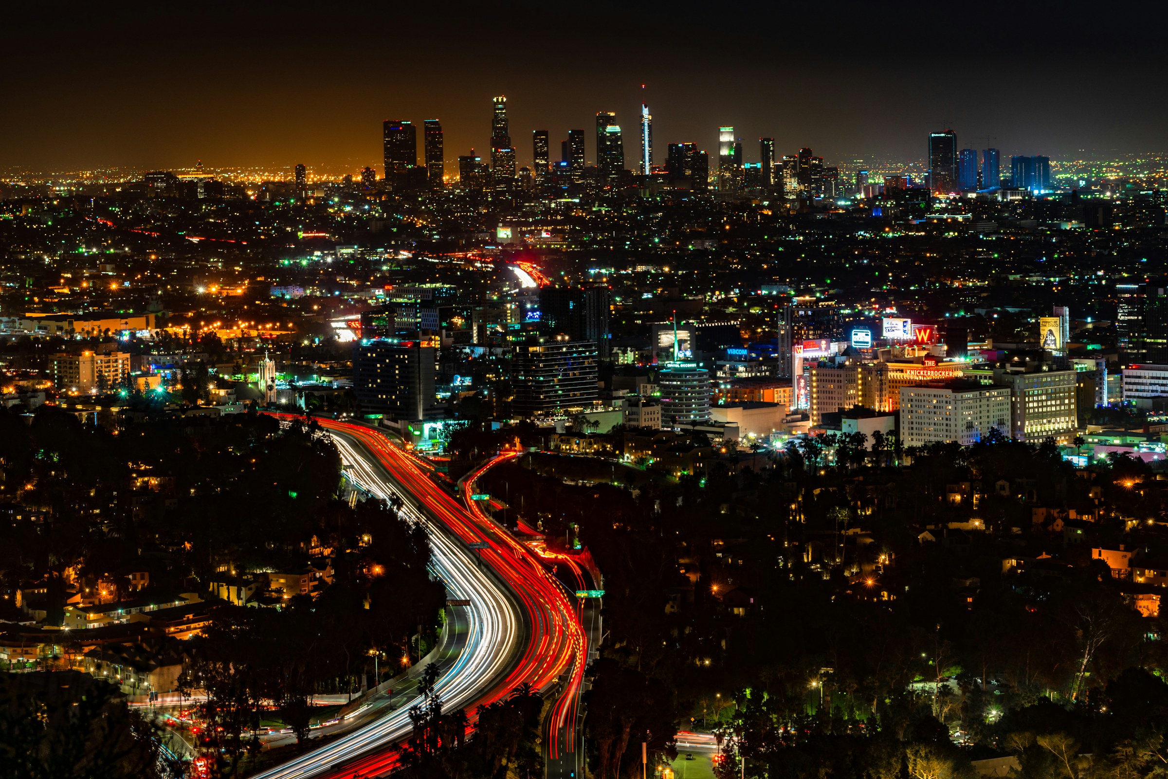 Downtown Los Angeles skyline at night with freeway traffic, seen from above